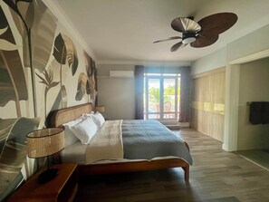 A bedroom with a bed, a ceiling fan, a window with curtains, and a view of the outside. - Lakaz Poz - Bed & Breakfast - 200m de la mer (Albion)