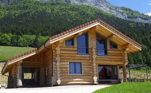 A log cabin with a sloped roof, large windows, and a covered porch. - Gites du Tilleul: Les Coulmes (RENCUREL)