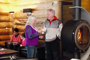 L’intérieur d’une cabane en rondins, avec un poêle à bois, des sièges en cuir et une cheminée.