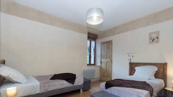 A bedroom with two single beds, a wooden wardrobe, a radiator, and a ceiling light fixture.