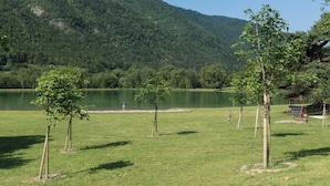 A grassy field with a lake and trees, a goalpost, and a person in the distance.