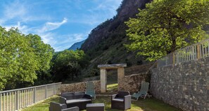 A patio area with outdoor furniture, a stone wall, and a view of a mountainous landscape.