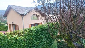 A two-story house with a tiled roof, a visible chimney, and a well-maintained hedge in the foreground. - LE CLOS FLEURI URIAGE (URIAGE LES BAINS)