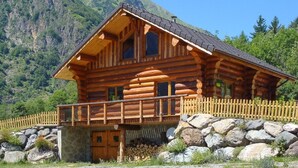 A log cabin with a balcony, surrounded by a stone wall and a wooden fence. - CHANTELOUVE / LE BECAN (CHANTEPERIER)