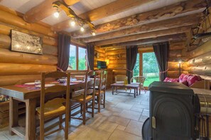 A log cabin interior with a dining area, a sofa, and a fireplace. - CHANTELOUVE / LE BECAN (CHANTEPERIER)