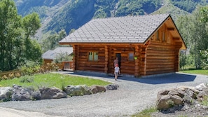 A wooden log cabin with a sloped roof, surrounded by a gravel driveway and a wooden fence. - CHANTELOUVE / LE BECAN (CHANTEPERIER)