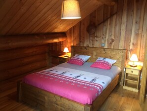 A wooden cabin bedroom with a bed, two bedside tables, and a hanging light fixture. - CHANTELOUVE / LE BECAN (CHANTEPERIER)