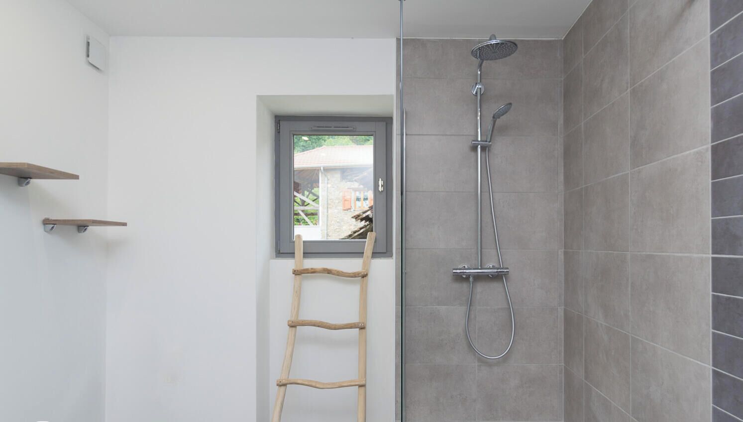 A shower area with a showerhead, a wooden ladder, and a window.