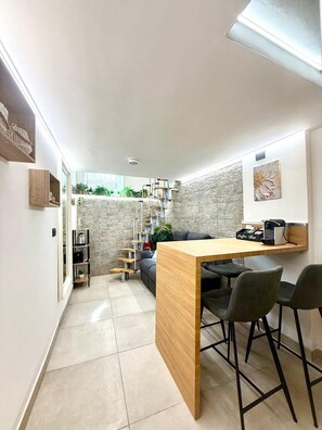 A compact kitchen with a wooden island, bar stools, and a coffee machine. - TrastevereSweetNook.Charming studio apartment located in the heart of Trastevere (Roma)