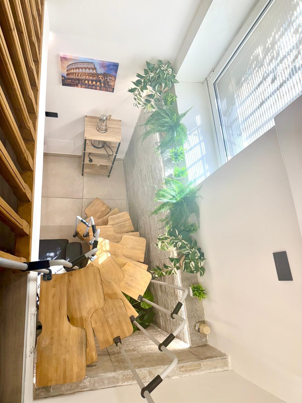 A staircase with a wooden design, a wall-mounted plant, and a picture of the Colosseum.
