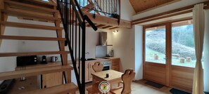 Eine Holztreppe führt zu einem Schlafzimmer im Zwischengeschoss mit Blick auf eine verschneite Landschaft.