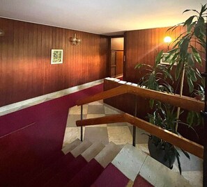 Una scala con ringhiere in legno, un tappeto rosso e una pianta in vaso.