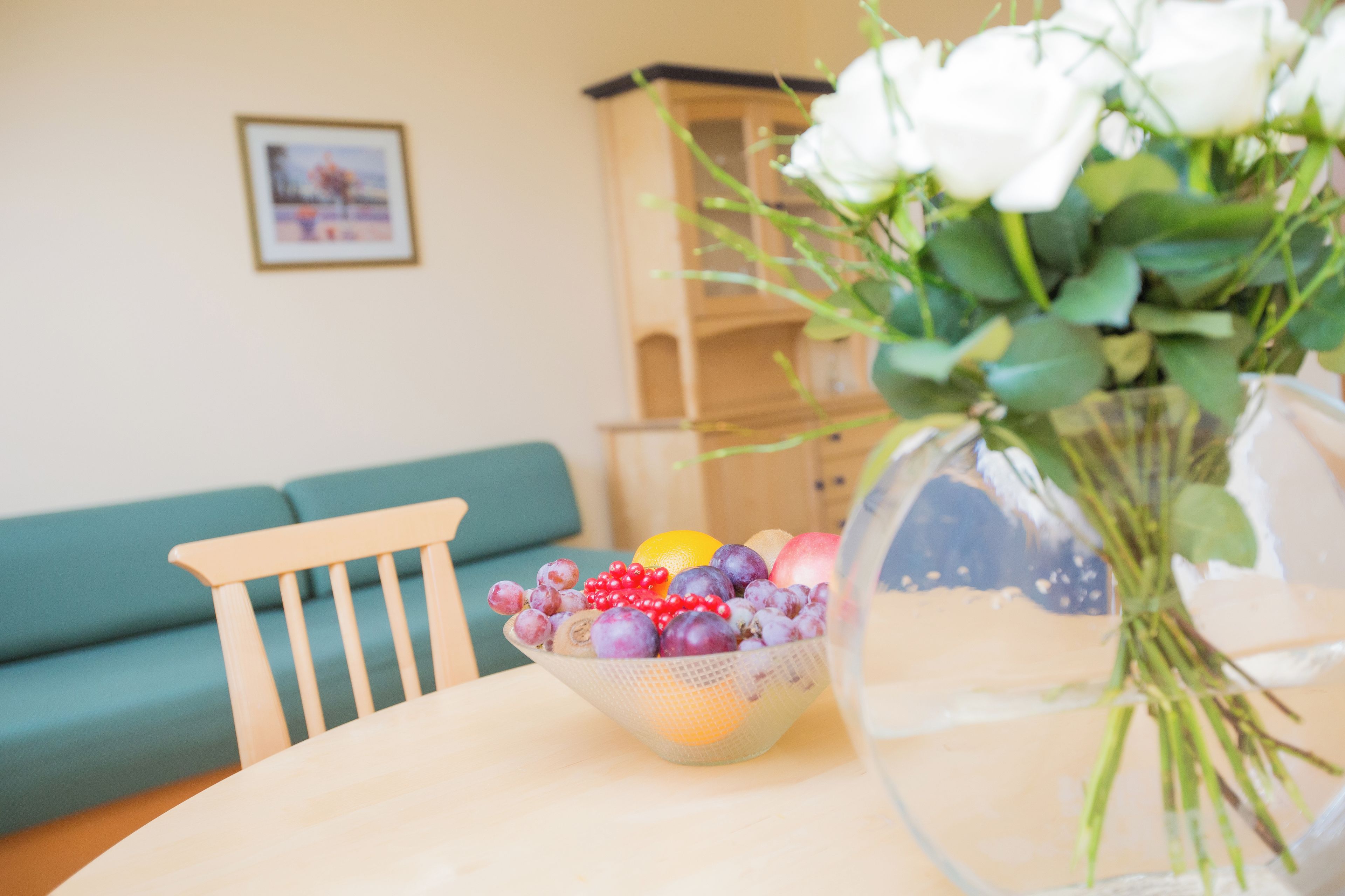 Ein Esstisch mit Obstschale und Blumenvase.