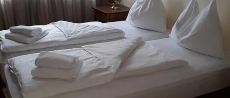 A hotel room with a neatly made bed, a bedside table with a lamp, and a framed picture on the wall.