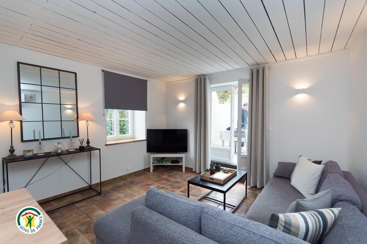 Un salon moderne comprenant un canapé, une table basse, un téléviseur et une console sur laquelle sont disposés des objets décoratifs.