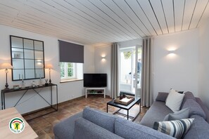 Ein modernes Wohnzimmer mit einer Couch, einem Couchtisch, einem Fernseher und einem Konsolentisch mit Dekorationselementen.