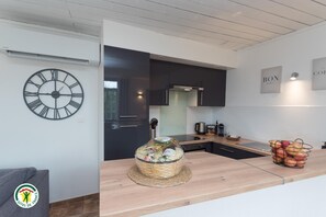 Une cuisine moderne avec un plan de travail en bois, une grande horloge et un panier de fruits.