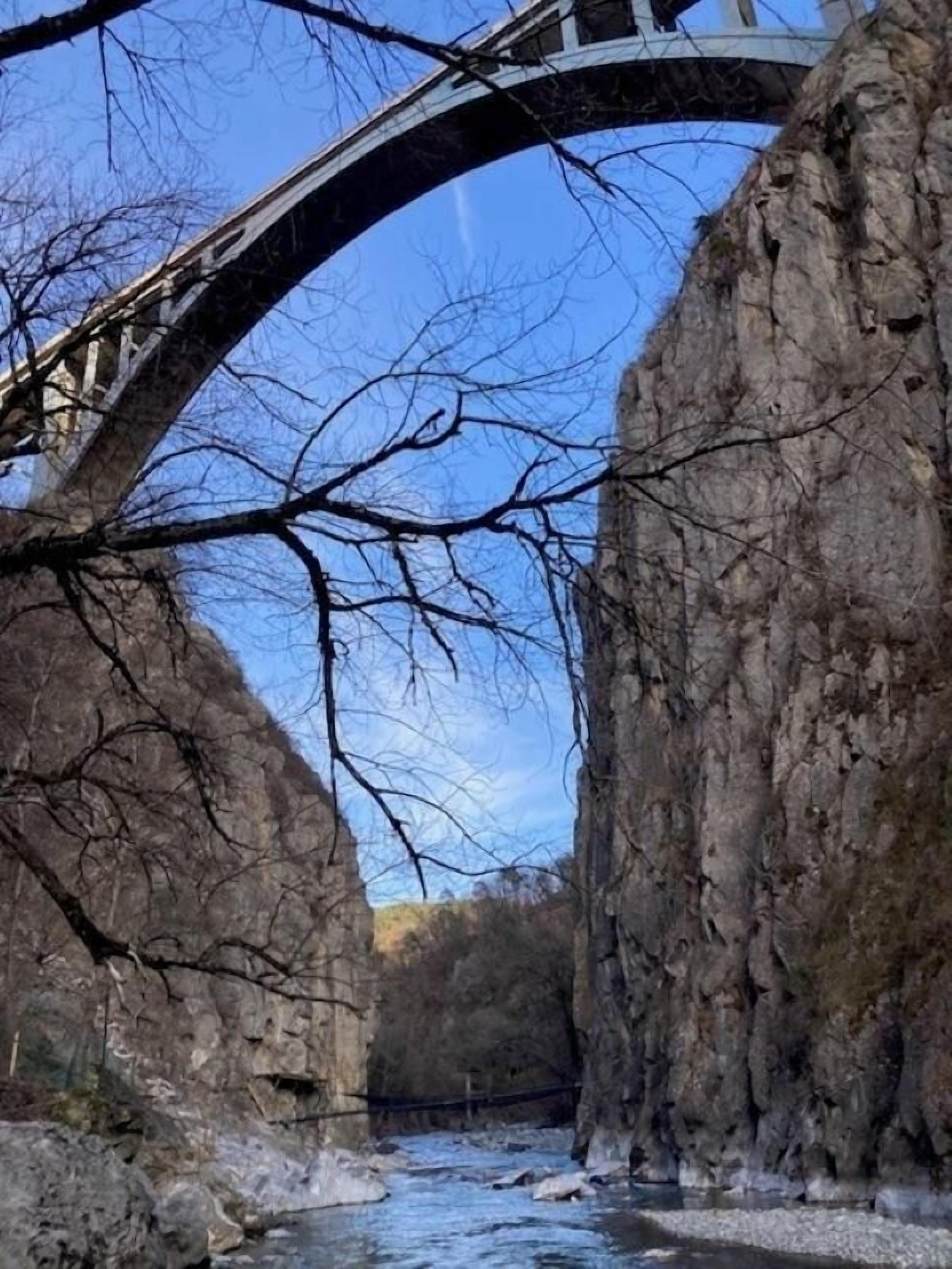 A bridge over a river with rocky cliffs on either side.