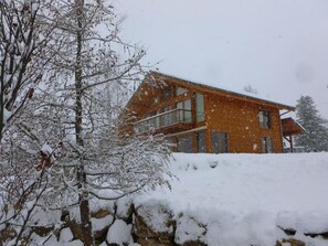 A two-story building with a brick exterior, surrounded by snow-covered trees and a stone wall. - The Wooden Case - PONSONNAS (PONSONNAS)