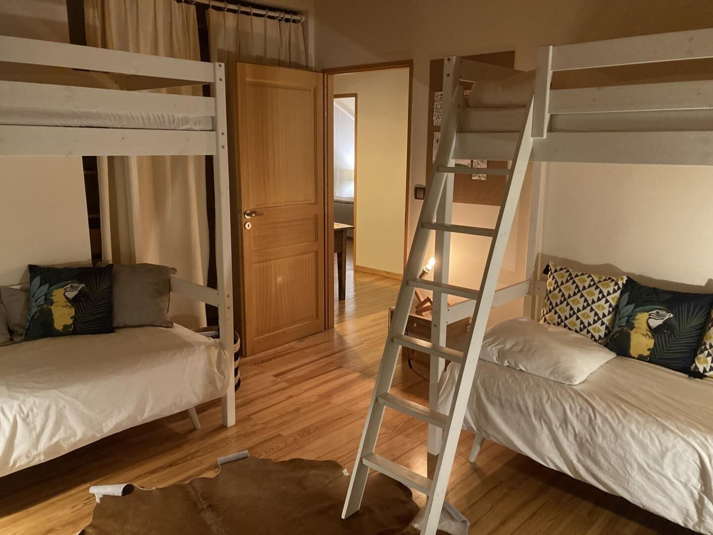A room with bunk beds, a ladder, a wooden door, and a small table.