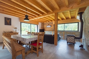 A wooden interior with a dining table, chairs, a sofa, and a fireplace. - From L'Arguille - LE HAUT-BREDA (LE HAUT-BREDA)