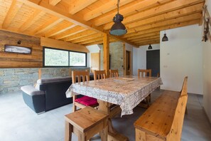 A dining area with a wooden table and benches, a stone wall, and a stone fireplace. - From L'Arguille - LE HAUT-BREDA (LE HAUT-BREDA)