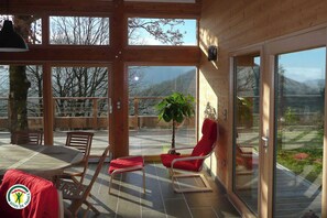 A wooden deck with a table, chairs, and a potted plant. - GITE des Orpins - L'ALBENC (L ALBENC)