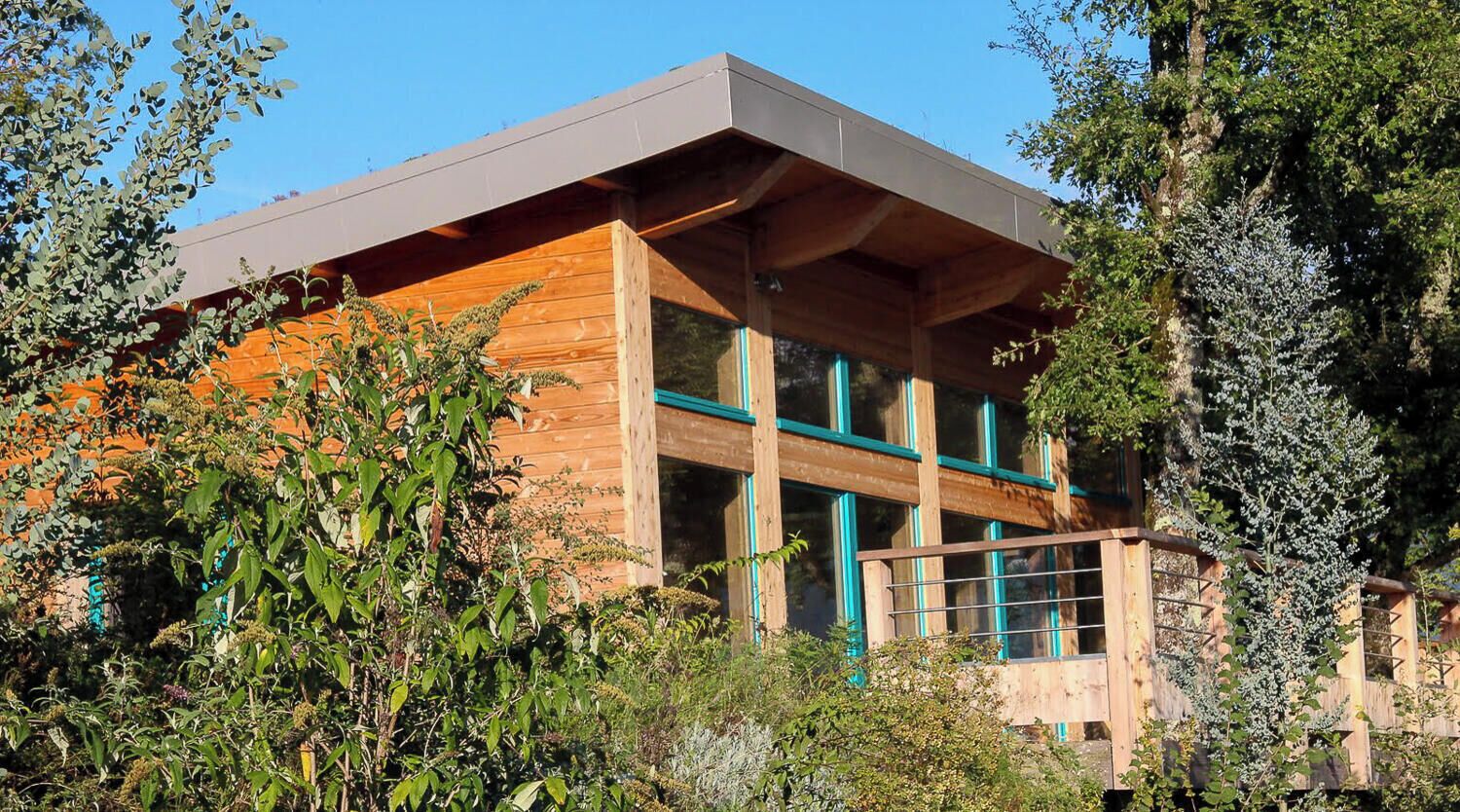 Een modern gebouw met een plat dak, grote ramen en een houten gevel.