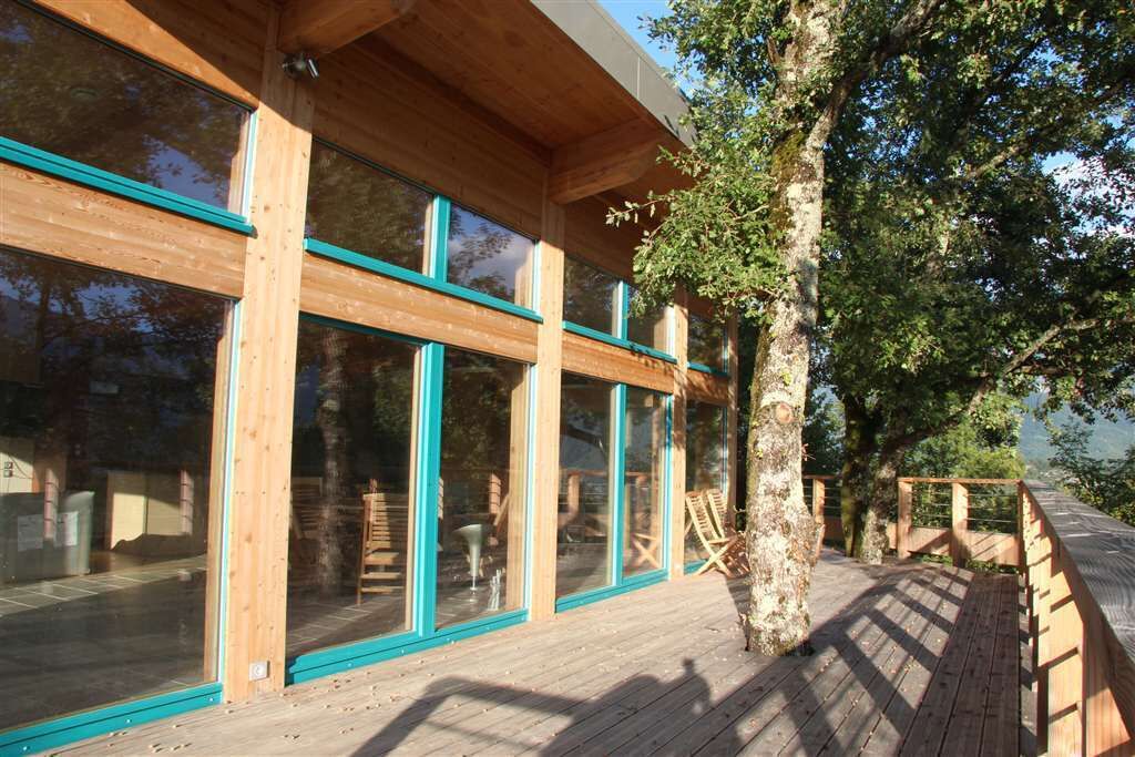 A wooden building with large windows and a deck.
