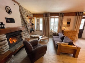 Una sala acogedora con chimenea de piedra, muebles de madera y vistas a través de una ventana.