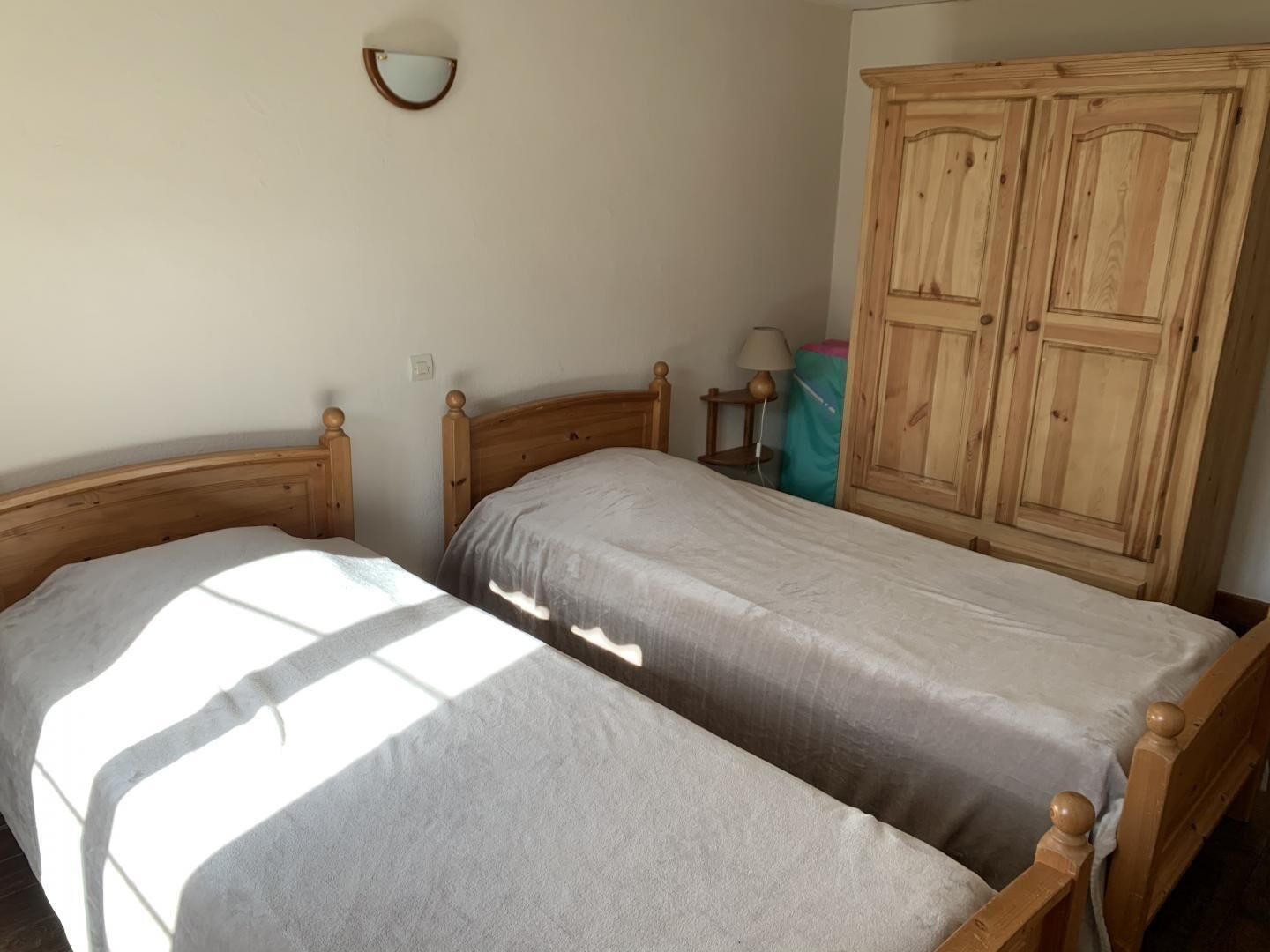 A bedroom with two wooden beds, a wardrobe, and a wall-mounted mirror.