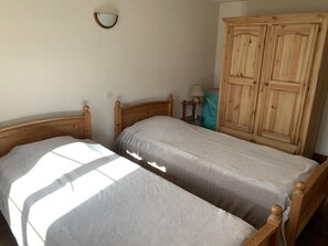 A bedroom with two wooden beds, a wardrobe, and a wall-mounted mirror. - From Jonan Farm - Tabor (SAINT HONORE)