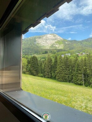 A window with a view of a green landscape, including trees and a mountain. - The Three Som - SAINT PIERRE DE CHARTREUSE (SAINT PIERRE DE CHARTREUSE)