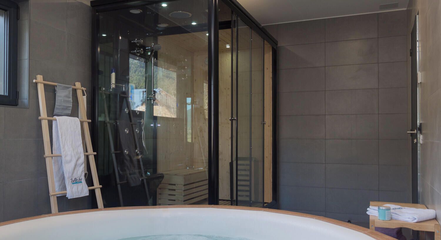 Une salle de bain moderne avec une douche à parois de verre, une échelle en bois et une baignoire.