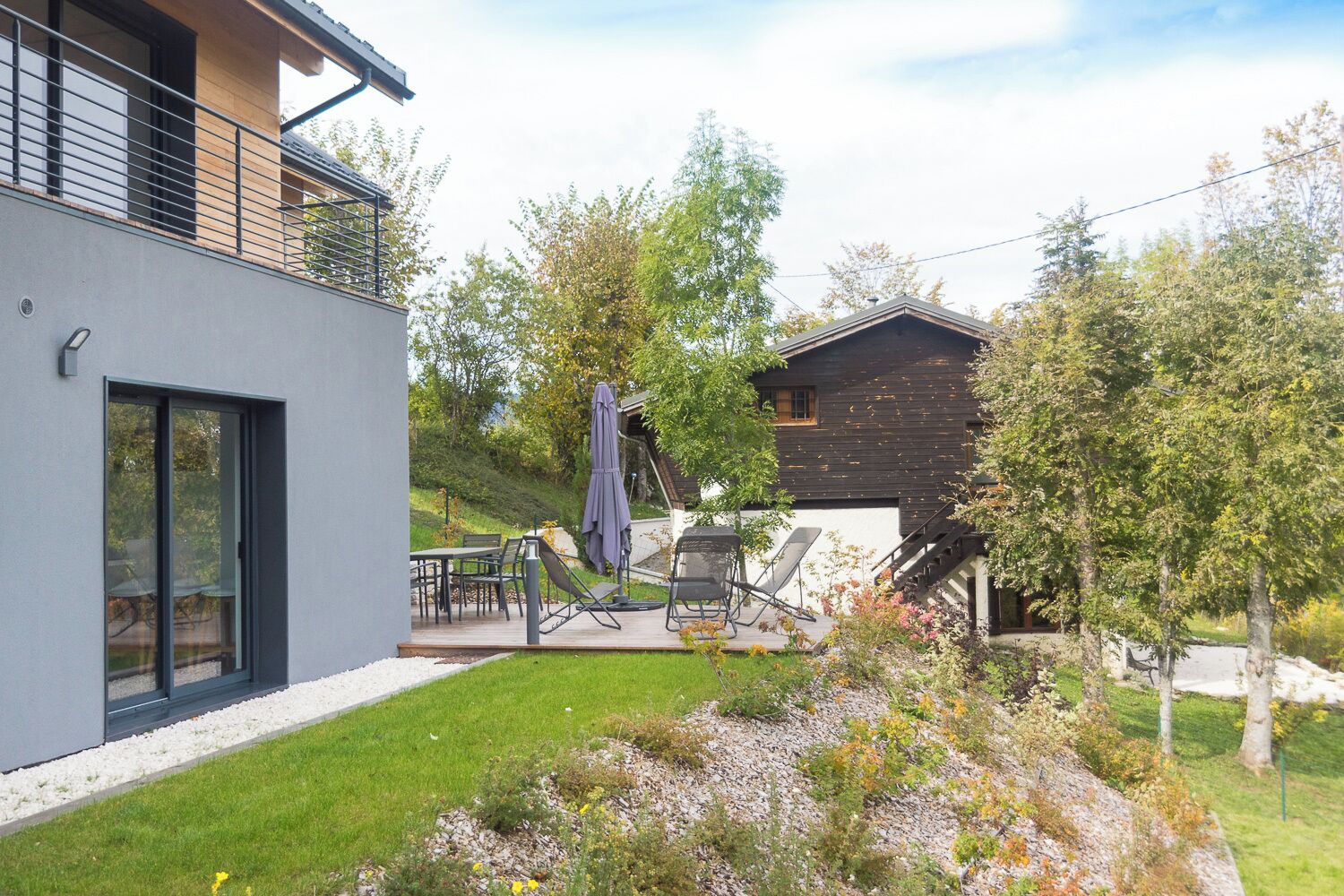 Une maison moderne dotée d’un patio, de mobilier d’extérieur et d’un jardin.