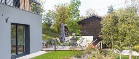 Une maison moderne dotée d’un patio, de mobilier d’extérieur et d’un jardin.