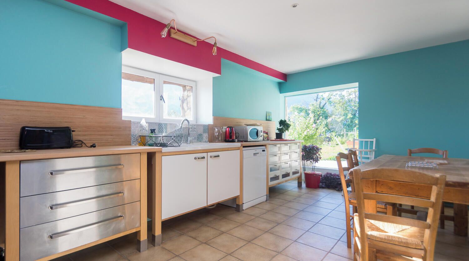 A kitchen with a dining area, a window, and a view of greenery.