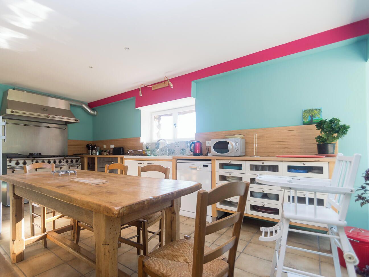 A kitchen with a wooden table and chairs, a microwave, and a stove.
