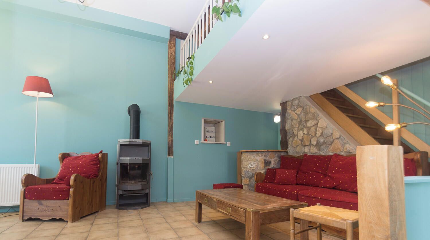Una sala de estar con chimenea, un sofá, una mesa de centro de madera y una lámpara roja.