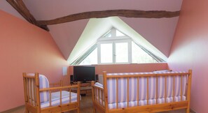Ein Zimmer mit zwei Holzbetten, einem Fernseher und einem Fenster.