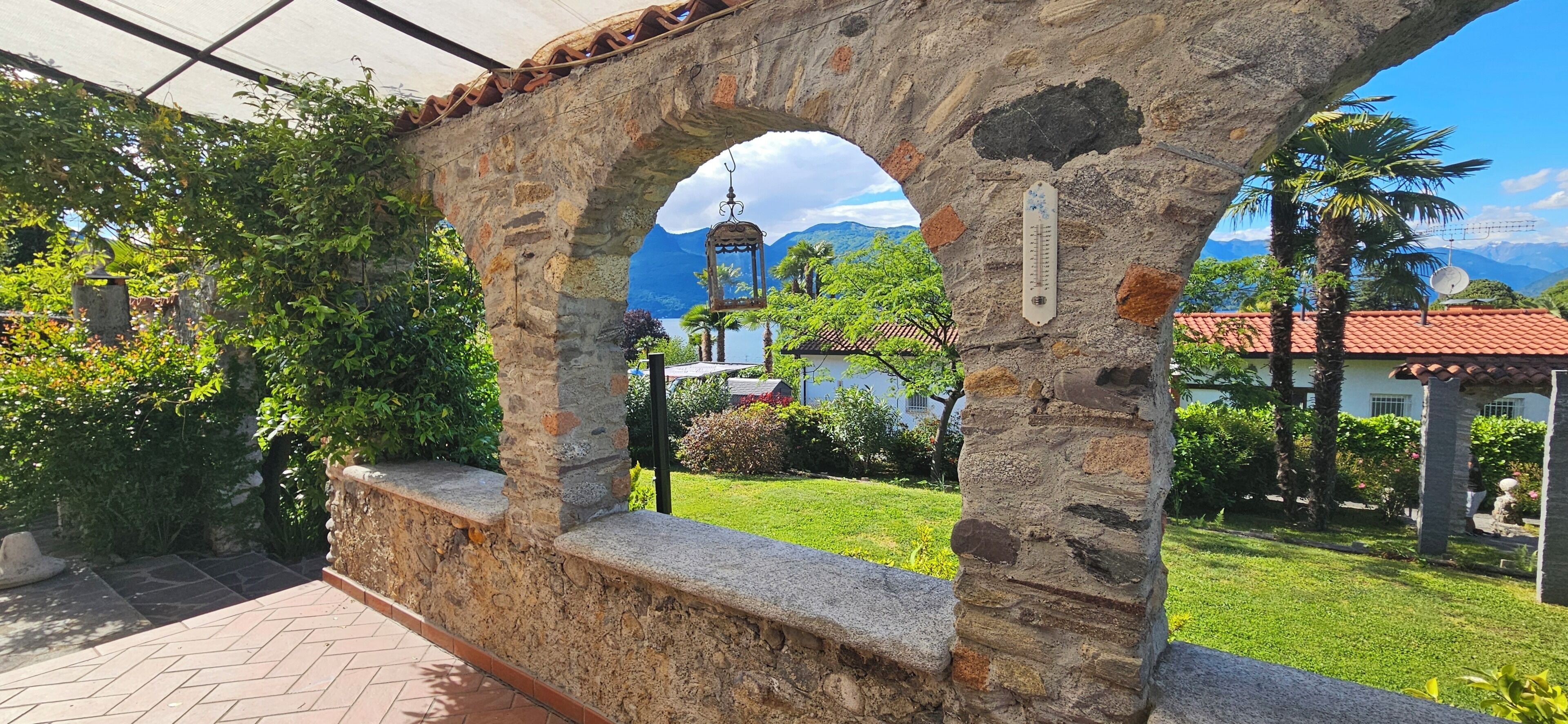 A stone archway with a view of a house and mountains.
