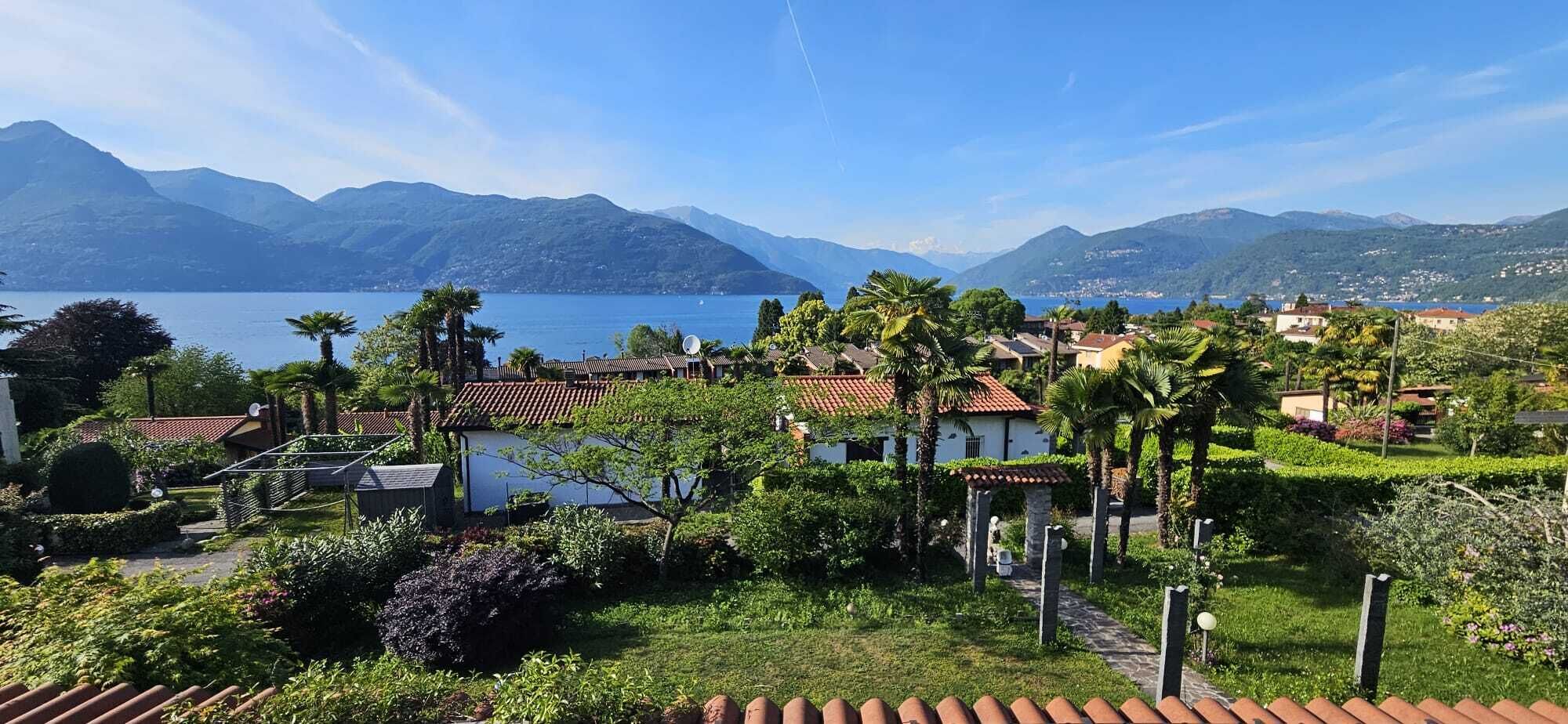 Un quartier résidentiel avec des maisons, un jardin et un lac, avec des montagnes en arrière-plan.