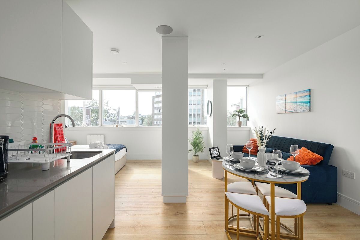 Una cocina moderna con comedor, armarios blancos y vistas a la ciudad.