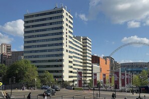 A multi-story building with a modern architectural design, featuring a prominent vertical sign on the facade. - Wembley Studio | Cinema, Gym & Workspace (England)