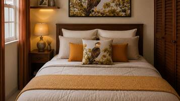 Une chambre à coucher avec un grand lit, une table de chevet avec une lampe, un tableau encadré au mur et une fenêtre avec des rideaux.
