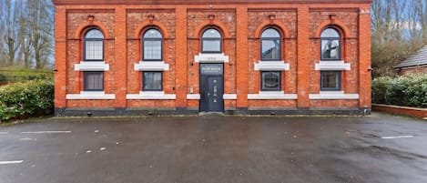 A red brick building with arched windows and a black door, labeled '1898 Pump House.'