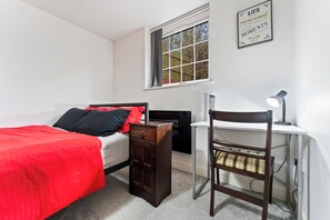A bedroom with a bed, a desk, a chair, a window, and a wall-mounted sign. - 2 Pump House (Birmingham)