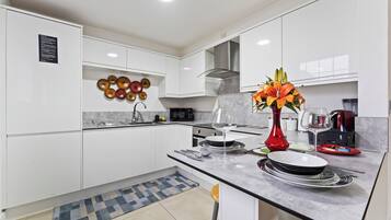 Una cocina moderna con armarios blancos, una isla central con un florero y un elemento decorativo en la pared.