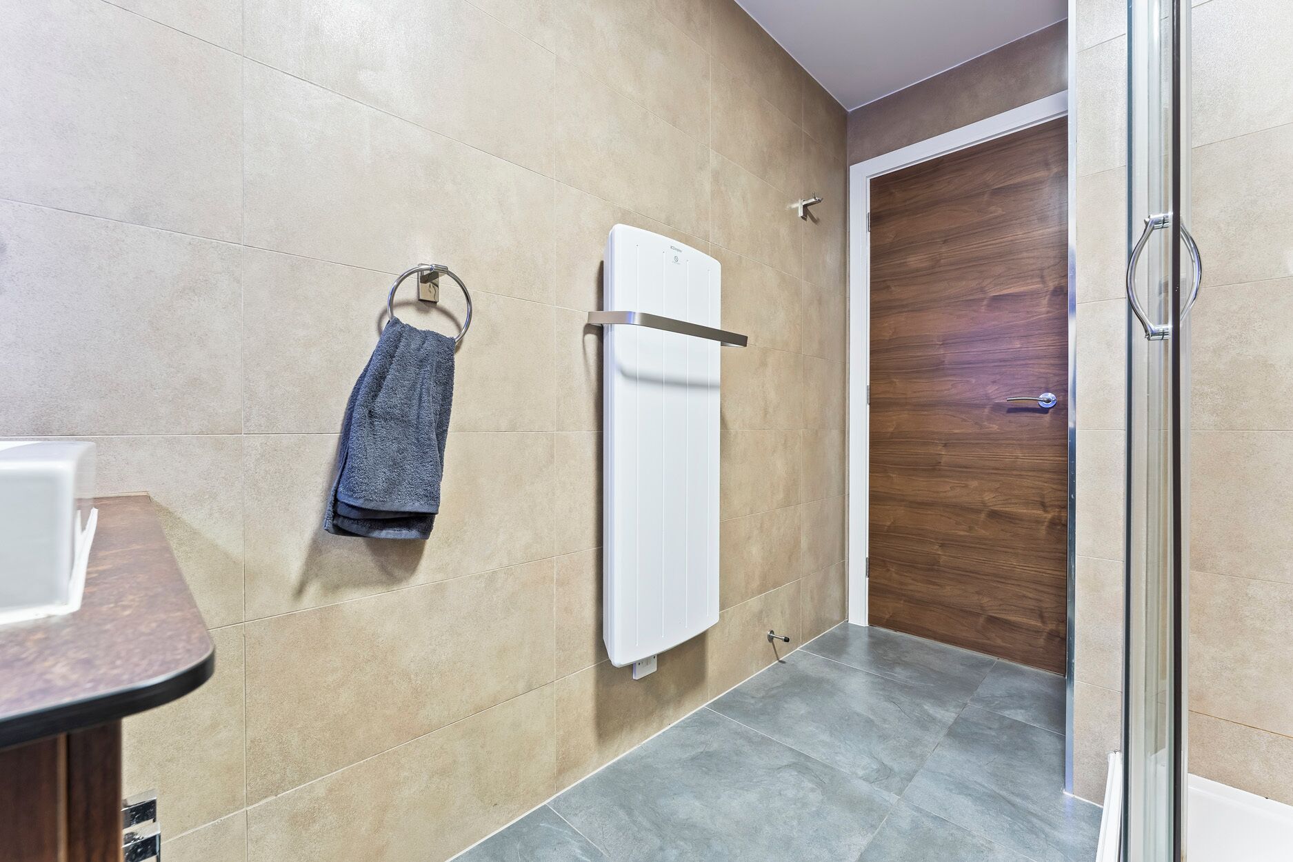 Un baño con un perchero, un radiador blanco y una puerta de madera.