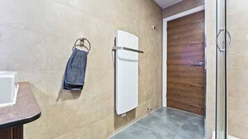 Un baño con un perchero, un radiador blanco y una puerta de madera.